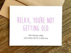 a card that says relax, you're not getting old on top of a wooden table