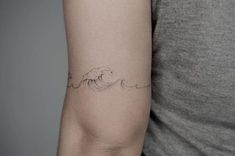 a woman's arm with a wave tattoo on the left side of her arm