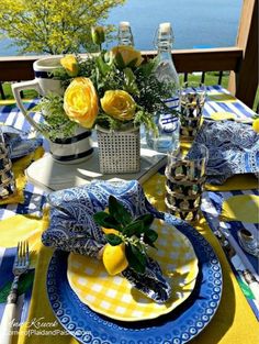 the table is set with blue and yellow plates, silverware, lemons and flowers