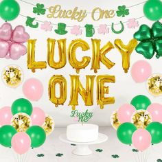 lucky one balloons and streamers in front of a cake with the words lucky one on it