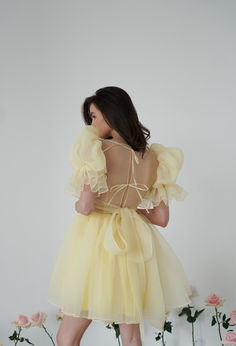 the back of a woman wearing a yellow dress with ruffles and bows on it