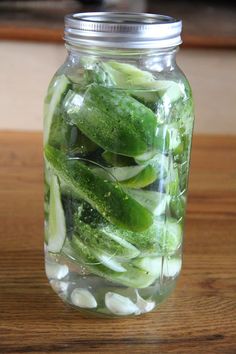 pickled cucumbers are in a mason jar on a wooden counter top,