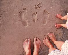 two people are standing in the sand with their feet up and one person is writing on the sand