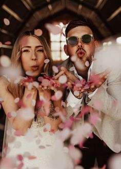 The bride and groom blowing pink, white and red confetti at their wedding in Wales Wedding Photos Funny Creative, Wedding Idea Photoshoot, Cheesy Wedding Photos, Wedding Photos Confetti, Colorful Confetti Wedding, Unique Couple Wedding Photos, Fun Wedding Photography Ideas, Wedding Photos In A Bar, Funky Wedding Photos