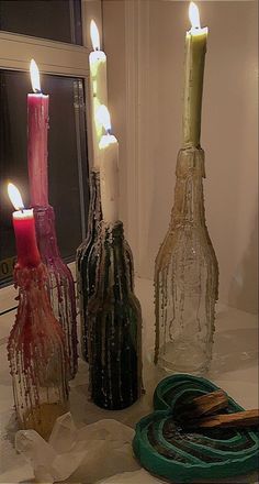 three bottles with candles in them sitting on a table