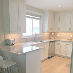 a kitchen with white cabinets and marble counter tops, along with two bar stools