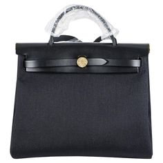 A chic Hermes Herbag Zip 31 handbag. The exterior of this Herbag features a top handle with a crossbody strap in Noir Vache Hunter leather on the top section whereas the body of the bag is made out of Noir Toile Militaire canvas, has a Clou de Selle closure and is accentuated with gold tone hardware. The back of the bag features a pocket pouch with a logo zipper pull. The body of the bag can be detached and replaced by a different body and this is the reason the Herbag is also known as the two-in-one bag. The interior is open and has a removable wallet pouch. The bag measures 31cm L x 24cm H x 10 cm D. Strap drop is 45cm. The bag is store fresh and comes complete with a Hermes Box, dust bag, clochette, lock, 2 keys and an copy of original receipt dated January 2024. Herbag Hermes, Hermes Wishlist, Basic Bags, Uni Bag, Trendy Heels, Kelly Bag, Vintage Hermes, Novelty Bags, Wallet Pouch