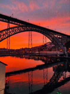 a bridge that is over some water at sunset