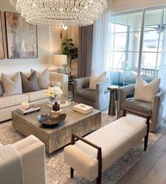 a living room filled with furniture and a chandelier hanging over the top of it