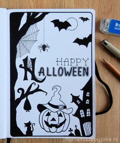 an open notebook with black and white halloween images on it, next to a camera