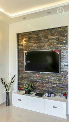 a flat screen tv mounted to the side of a brick wall in a living room