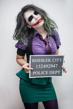 a woman dressed as the joker holding a sign