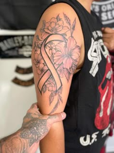 a man with a flower tattoo on his arm holding onto another person's arm