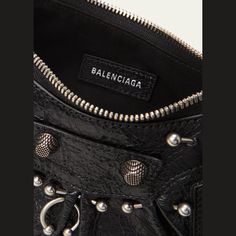 Balenciaga "Le Cagole" lambskin leather shoulder bag with ring piercings  Features signature stud and buckle hardware  Adjustable buckle shoulder strap with braided trim  Zip top closure with knot leather pull strap  Exterior, removable zip pouch bag and heart mirror  Cotton lining  Approx. 6.3"H x 10.2"W x 2.7"D Wipe clean Made in Italy Designer Bags With Rivets, Luxury Shoulder Bag With Rivets, Heart Mirror, Zip Pouch, Leather Pulls, Pouch Bag, Zip Top, Lambskin Leather, Leather Shoulder Bag