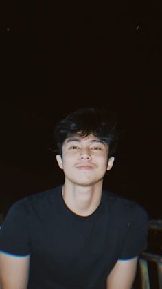 a young man sitting in front of a black background