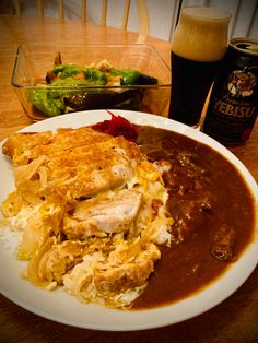 a white plate topped with food next to a glass filled with liquid and a beer