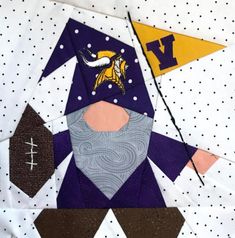 a close up of a patchwork quilt with a gnome face on it and two pennants