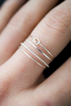 a woman's hand wearing a silver ring with three thin rings on top of it