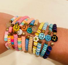 a person's arm with several bracelets that have smiley faces and buttons on them