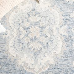 a blue and white rug with tassels on top of it next to a pillow