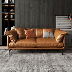 a brown leather couch sitting on top of a carpeted floor next to a book shelf