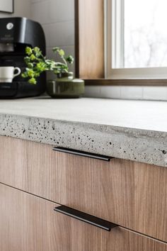 a kitchen counter top with black handles and a coffee maker in the backgrouund