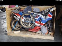 there is a motorcycle in the back of a wooden storage box with it's front tire missing