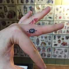 a person's hand with an evil eye tattoo on their left thumb and finger