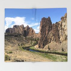 an open book with mountains in the background and water running through it, on a white surface