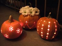 three orange pumpkins sitting on top of a table next to white flowers and candles