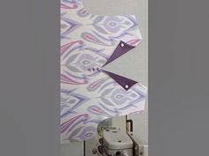 a camera and some paper on a white table with a purple object in the background