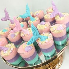 there are many little mermaid desserts on the table with gold rimmed dishes and cups