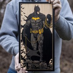 a man holding up a batman poster in front of his face