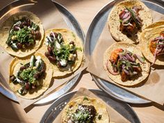 four different types of tacos on metal trays