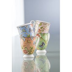 three colorful cups sitting next to each other on top of a glass table with reflections