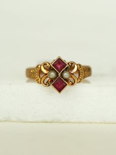 Her dainty Victorian style with gold work scrolls frame a powerful pair of Pearls and two stacked Rubies, set in a 10k gold band.  She's a fine addition to your collection.      	Ladies Size 6  	10k Yellow Gold Band  	Two Ruby red stones, pearls  	Arrives in gift box  Exclusively from Erin Pelicano Curated Vintage Collection. Each piece is intentionally chosen, pre owned, and ready to be loved and cherished again. sold as shown.  Shop the Curated Vintage Collection Dainty Vintage Jewelry, Pearl Jewelry Aesthetic, Victorian Wedding Ring, Vintage Ruby Ring, Ruby Ring Designs, Vintage Gold Jewelry, Antique Ruby Ring, Cute Promise Rings