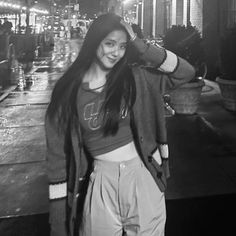 a woman standing in front of a building at night with her hair blowing in the wind