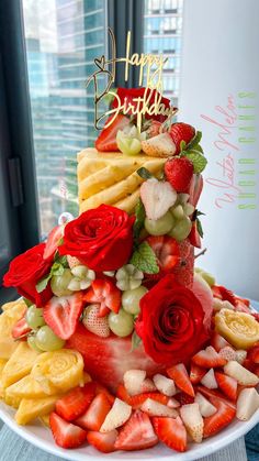 a birthday cake made out of fruit and flowers on top of a table with the words happy birthday written above it