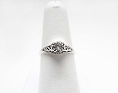 a diamond ring sitting on top of a white cloth covered napkin with an engraving design