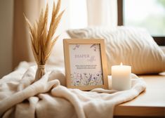 a photo frame sitting on top of a bed next to a candle