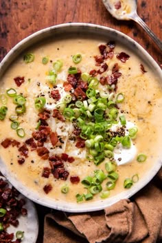 a bowl of soup with bacon, green onions and cheese