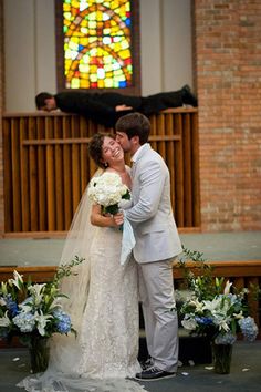 a bride and groom kissing in front of a stained glass window at their wedding ceremony