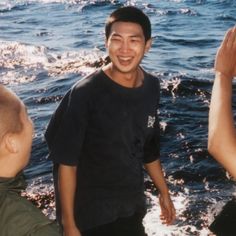 two men are standing in the water and one man is holding his hands up to him