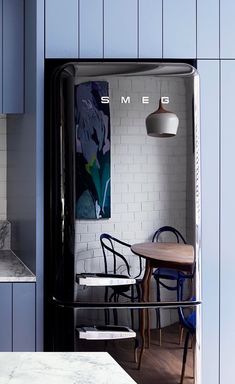 a kitchen with blue walls and white tile on the back wall is seen through an open door