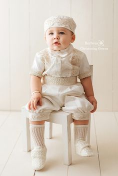 a baby sitting on top of a white chair wearing socks and a dress with lace