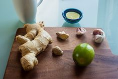 ginger, lime and garlic are on a cutting board next to a pitcher of dressing