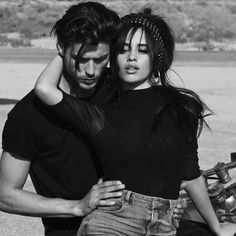 a man and woman standing next to each other in front of a motorbike