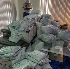 a pile of boxes sitting on top of a blue carpeted floor next to a window