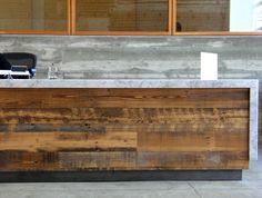 an office counter made out of wood and concrete, with a chair in the background