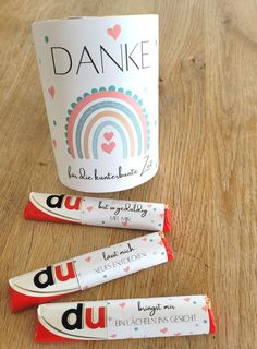 three candy bars sitting on top of a wooden table next to a cup with the word danke written on it